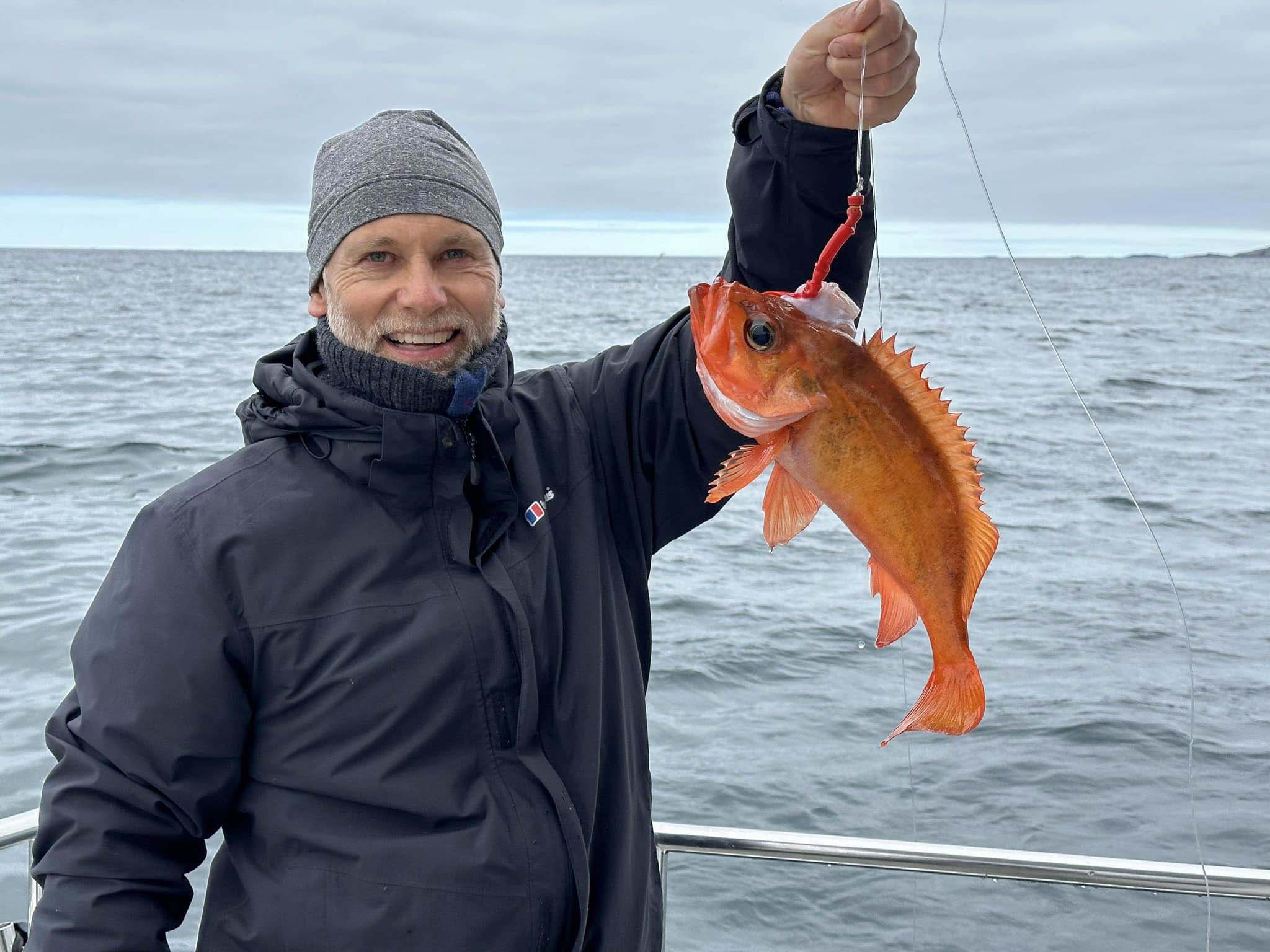 Glad står med fangst i hånden på fisketur med Skipnes Event.