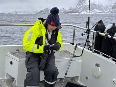 Dame på fisketur og betrakter fangsten i kassen.