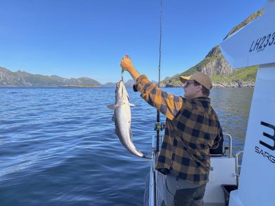 Gjest på fisketur og viser fram fangsten på kroken.