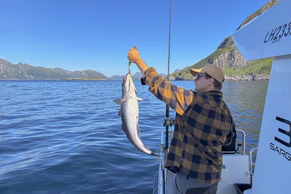 Gjest på fisketur og viser fram fangsten på kroken.